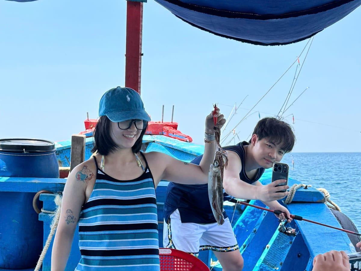 Two guests fishing under the boat canopy on an inshore day trip in Da Nang